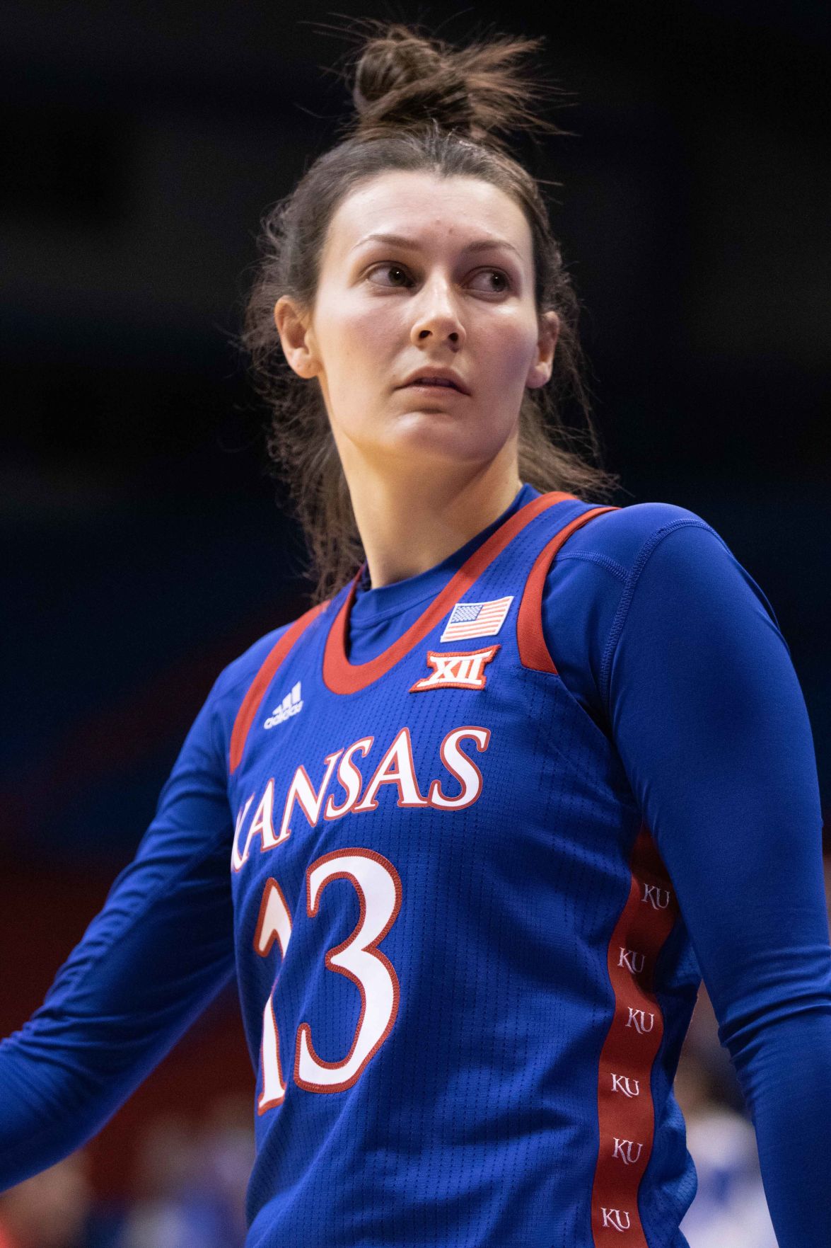 Half-length portrait of Holly Kersgieter who looks to the side with her arms beside her